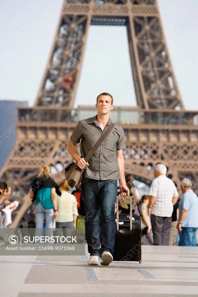 Male tourist walking with luggage, Eiffel Tower, Paris, France