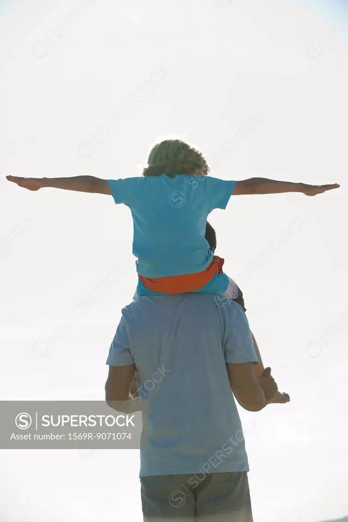 Boy riding on father´s shoulders, rear view