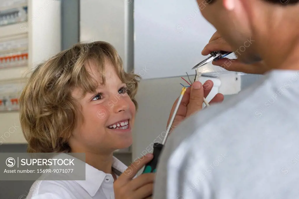 Boy helping father fixing wires