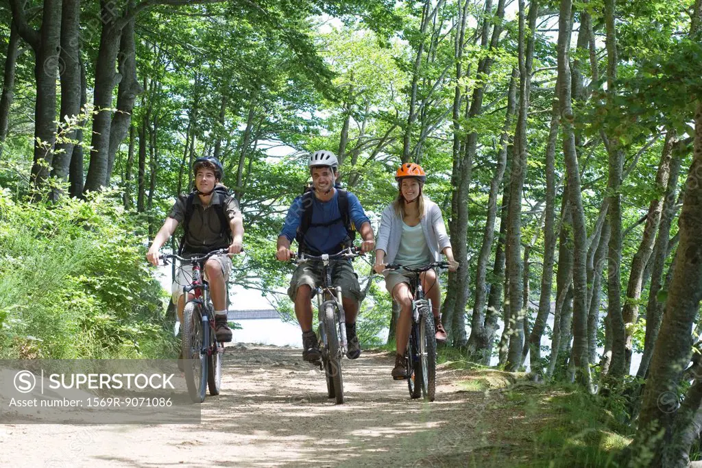 Friends riding bicycles side by side through woods