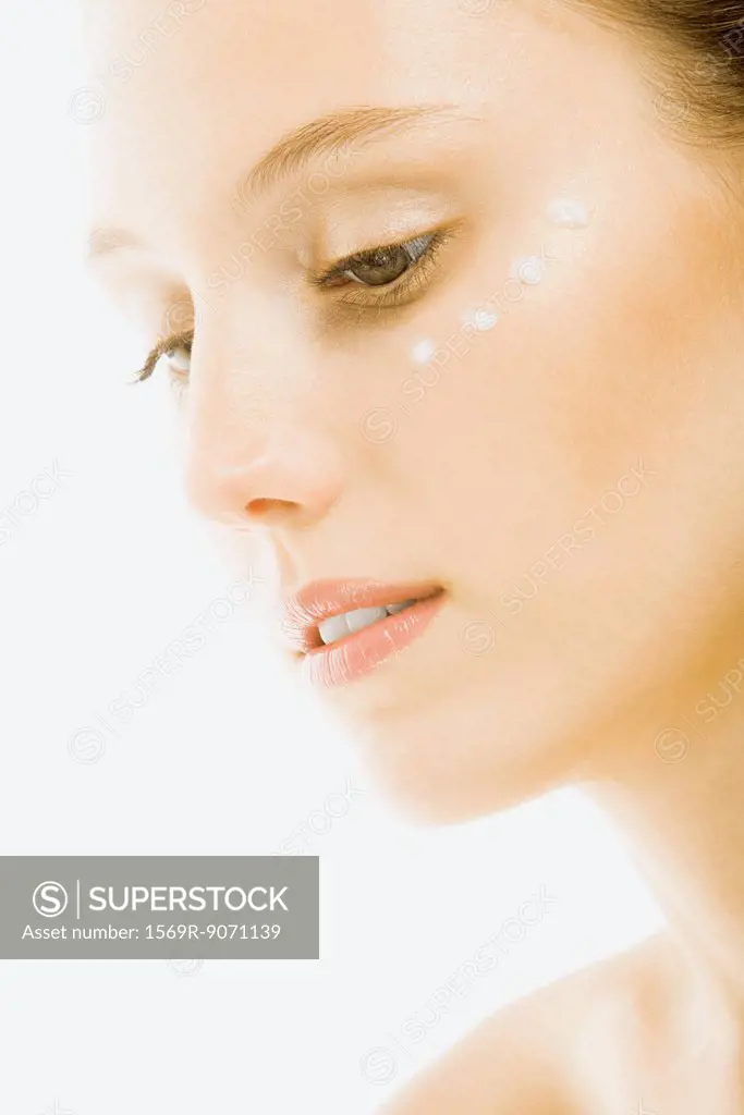 Woman with dots of undereye cream applied beneath eye, close_up