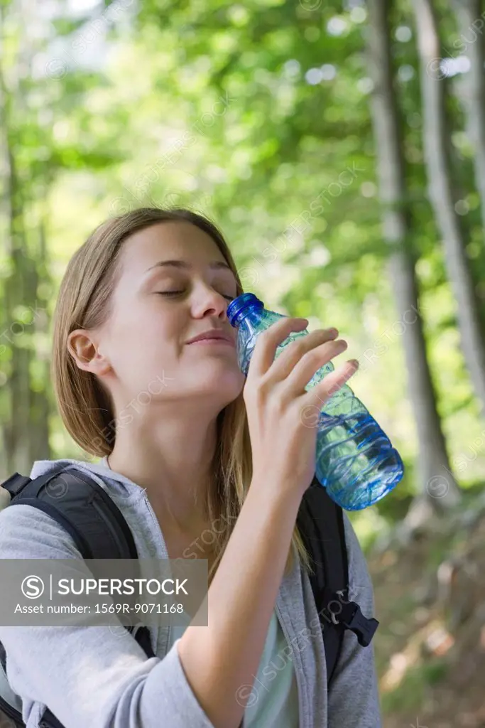 Woman drinking bottled water in woods