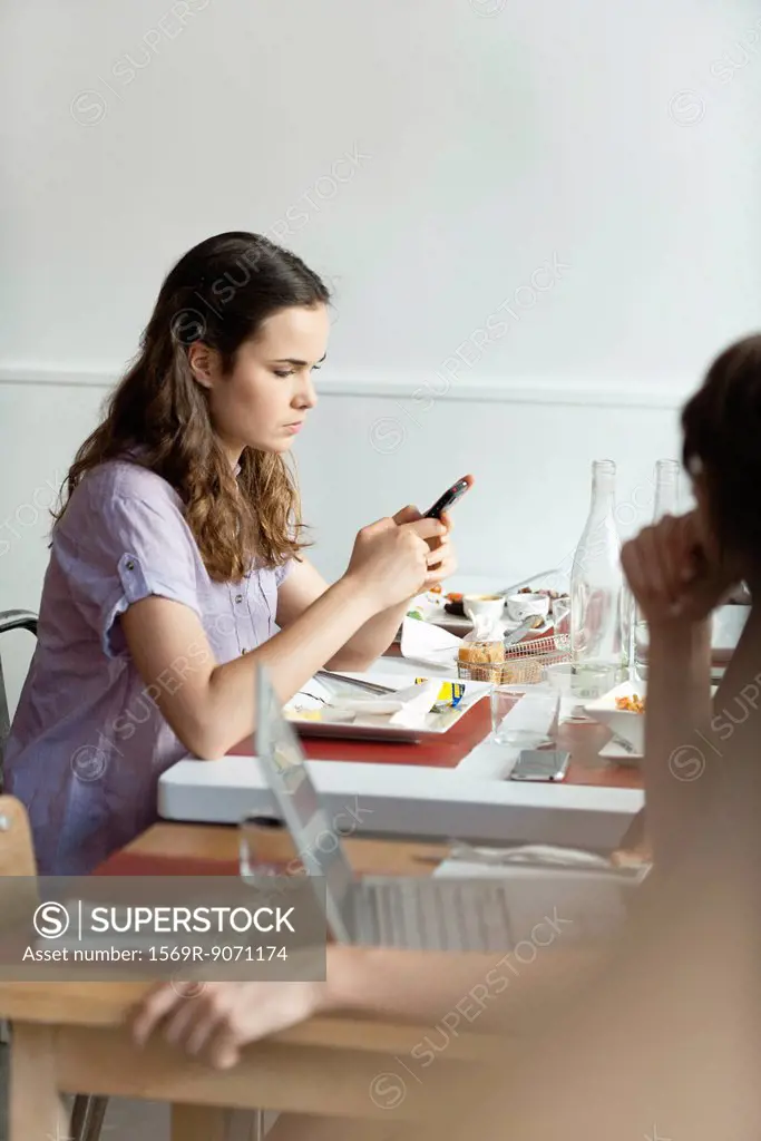 Young woman text messaging in restaurant