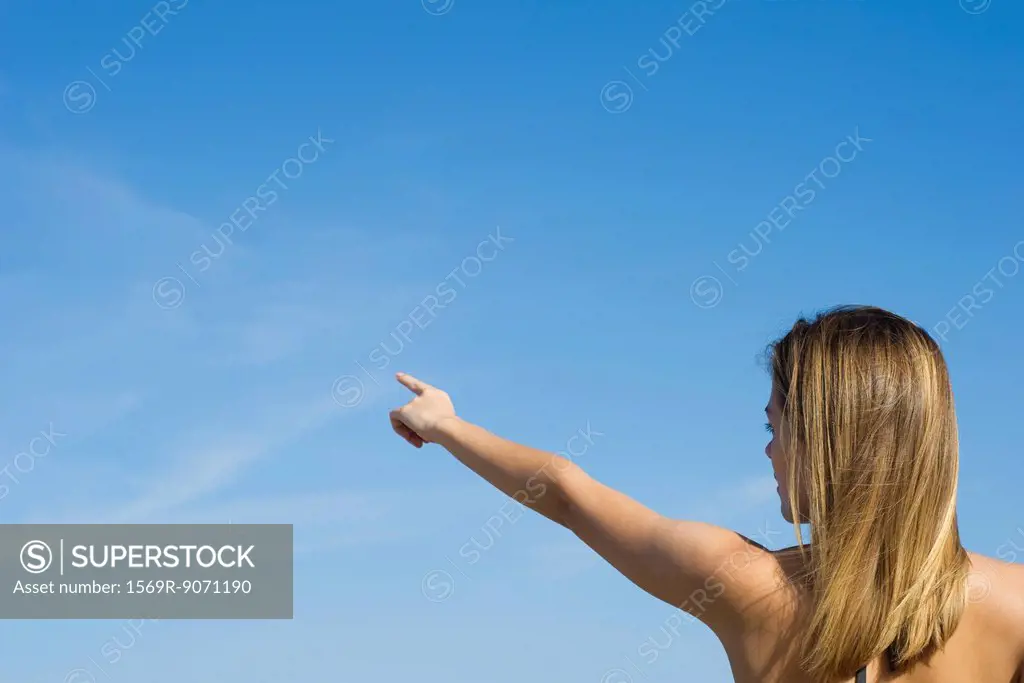 Woman pointing at the sky, rear view