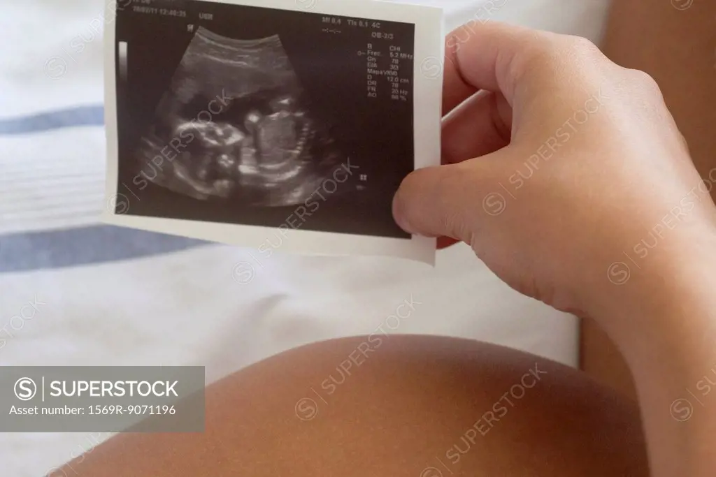 Pregnant woman holding ultrasound, cropped