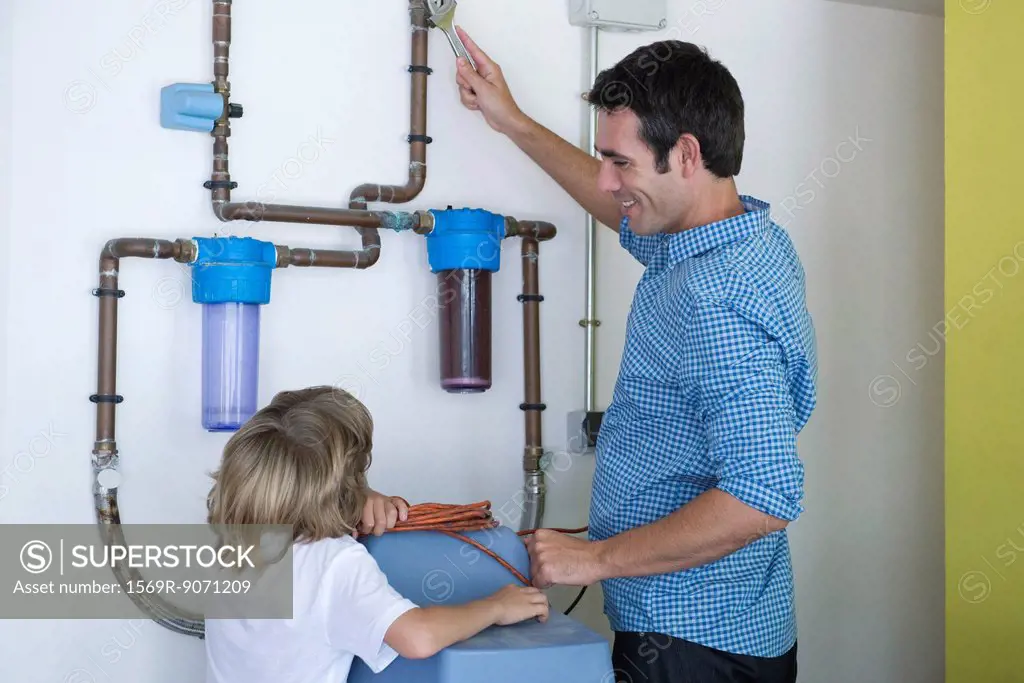 Boy watching father repairing home water filtration system