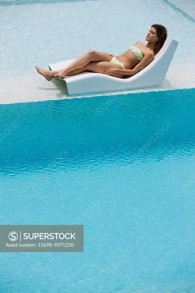 Young woman sunbathing by pool
