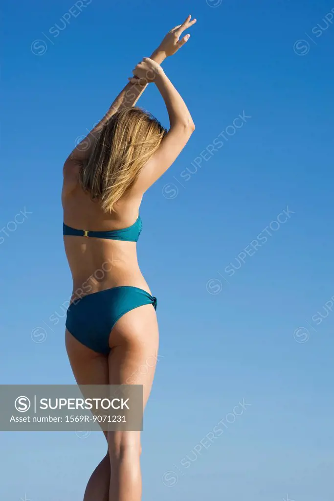 Woman in bikini stretching, rear view