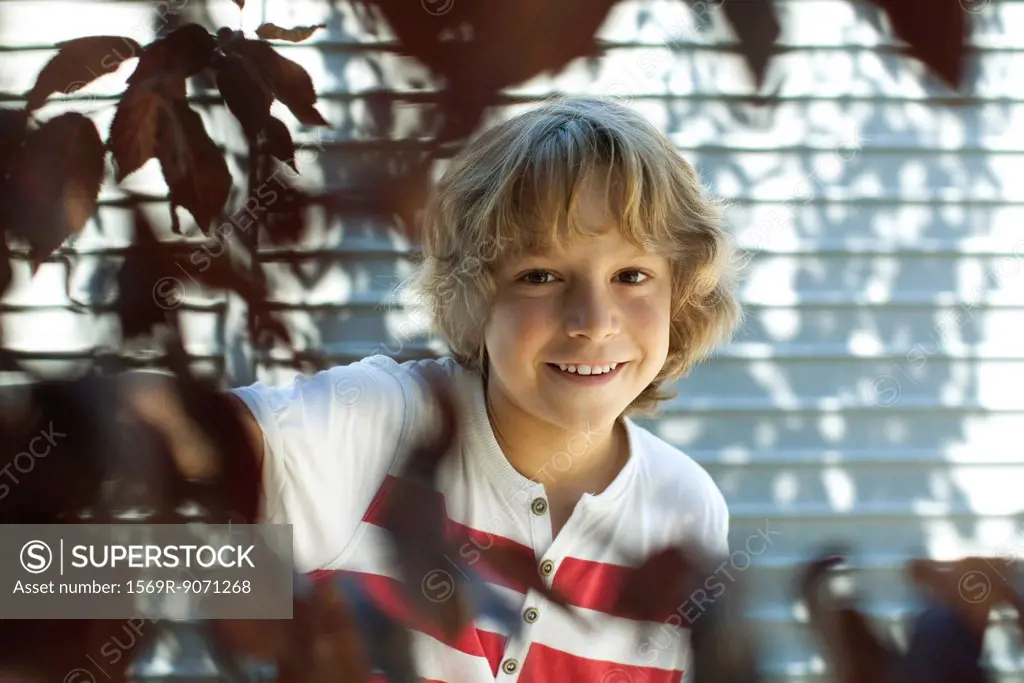 Boy smiling behind tree branches