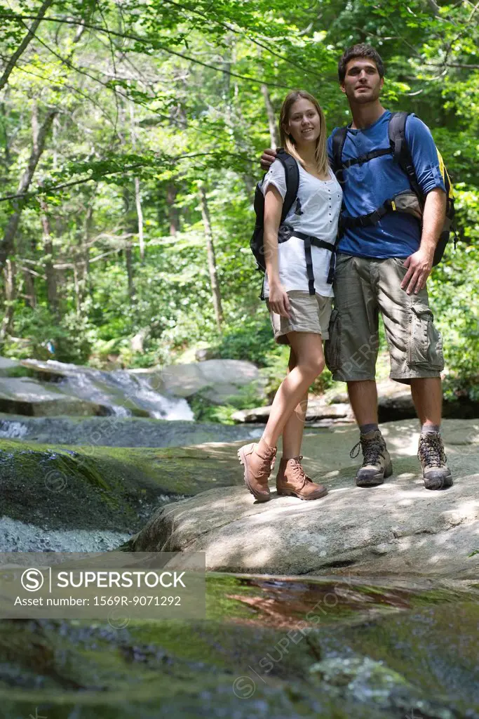 Couple standing by stream in woods