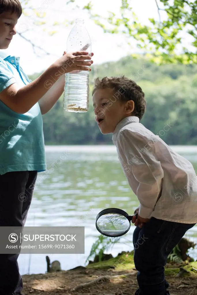 Children studying fish in water bottle