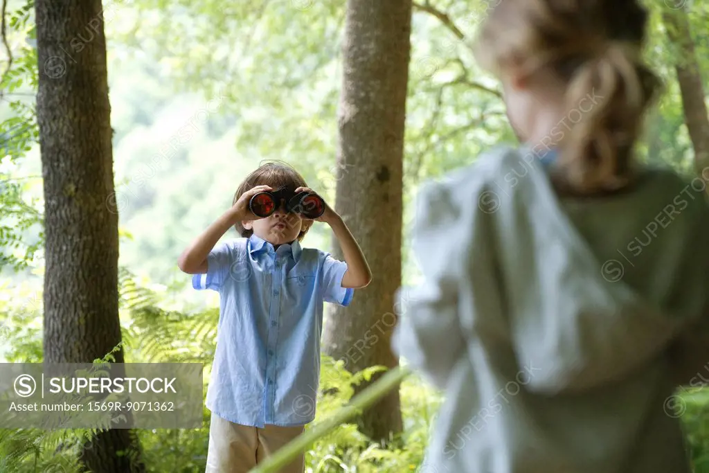 Children in woods, boy looking through binoculars