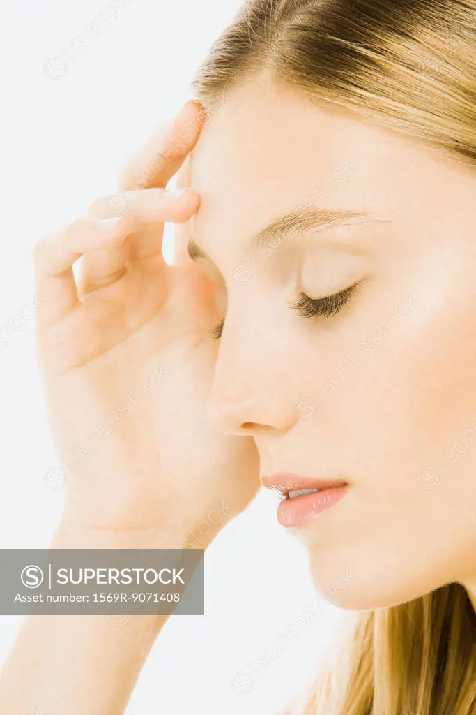 Woman with eyes closed, touching forehead, side view