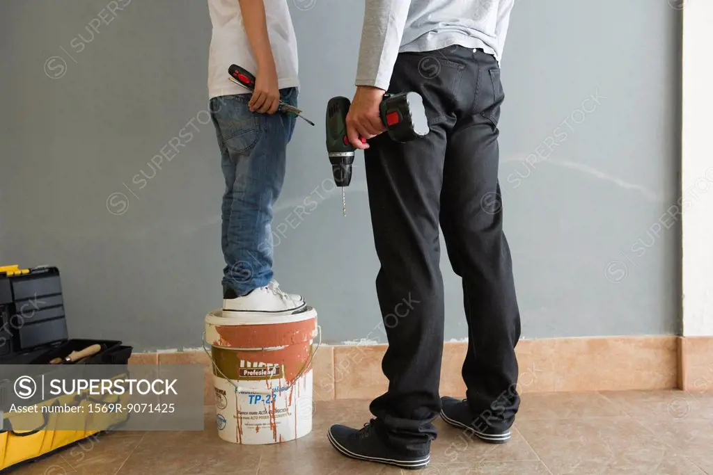 Father and son doing home improvement, low section