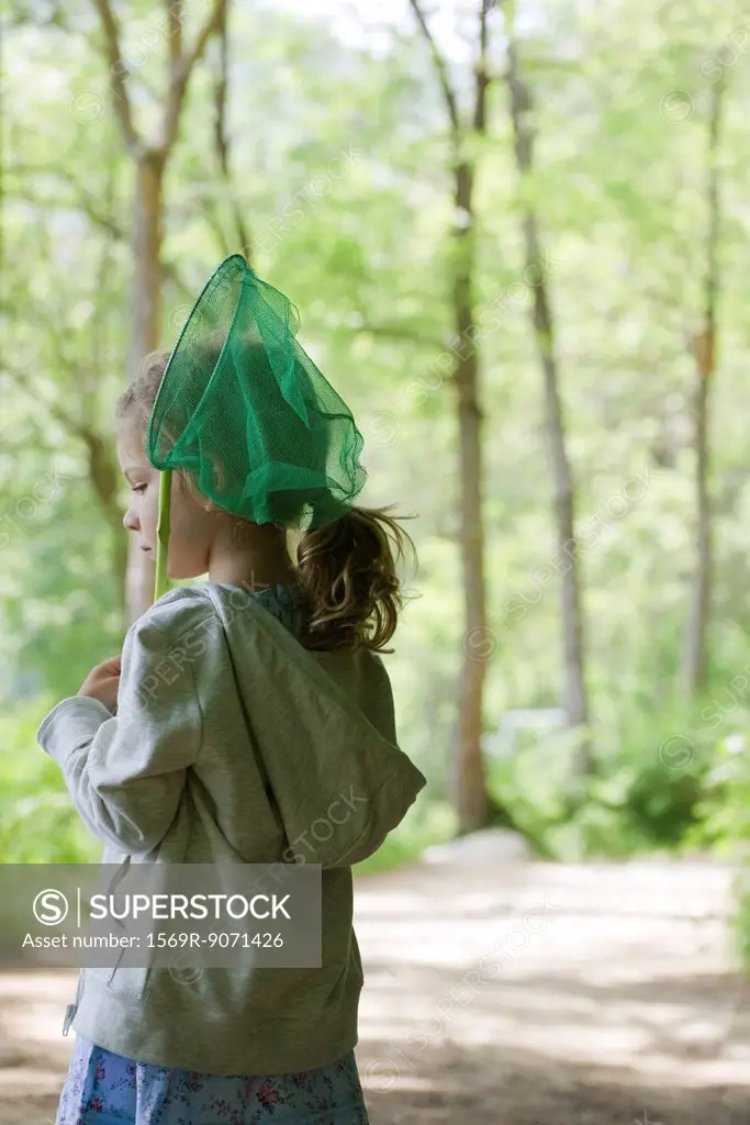 Girl carrying butterfly net in woods