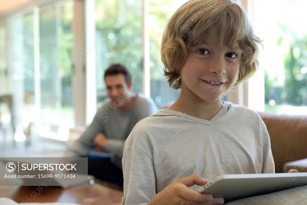 Boy holding digital tablet in living room