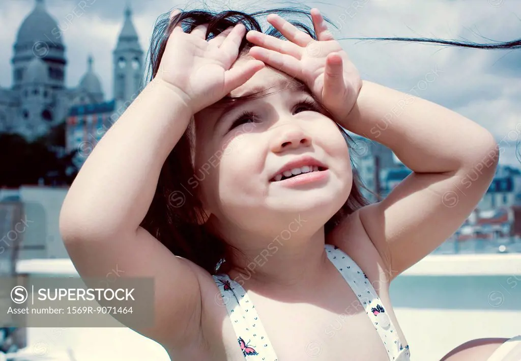 Little girl looking up, hands shading eyes