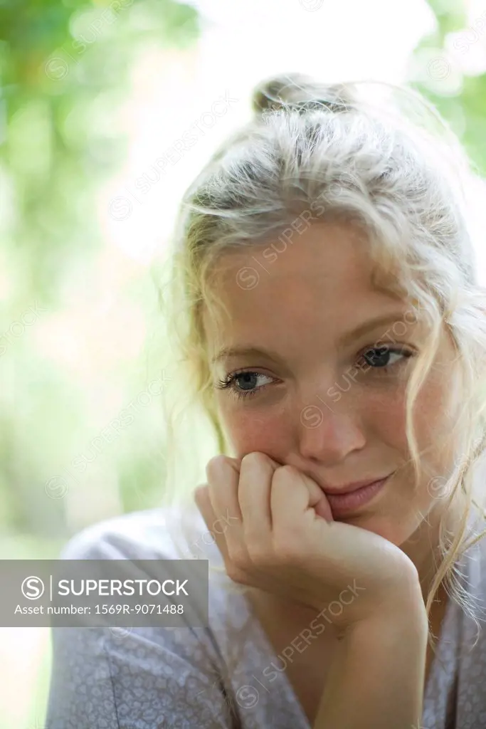 Woman with chin resting on hand, looking away in thought