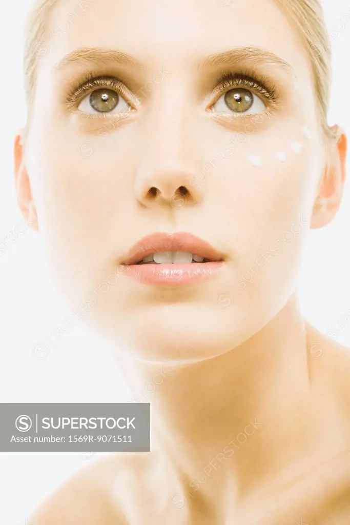 Young woman with dollops of undereye cream on face, portrait, close_up
