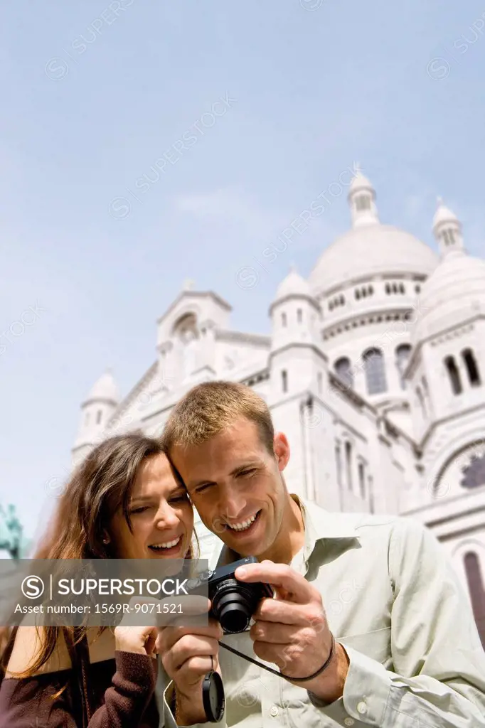 Sightseeing couple looking at digital camera, Sacre Coeur, Montmartre, Paris, France