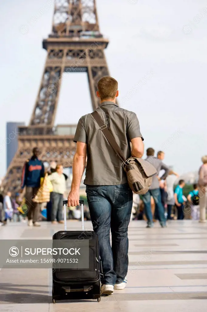 Male tourist walking with luggage, Eiffel Tower, Paris, France