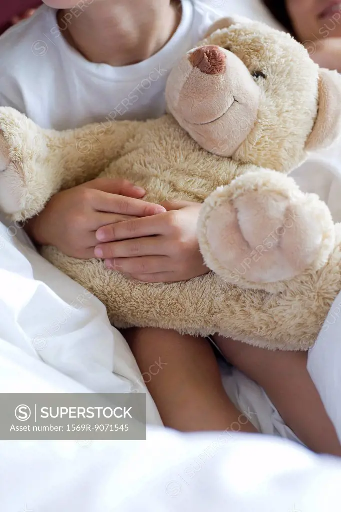 Child hugging teddy bear, cropped