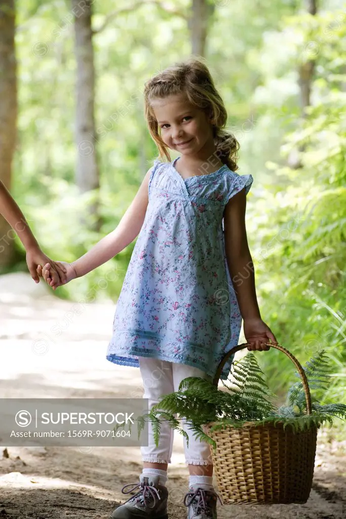 Girl carrying basket filled with fern fronds