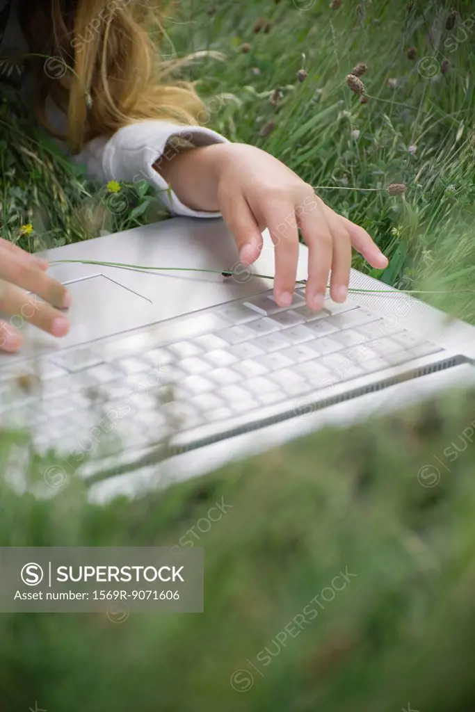 Girl lying in grass, using laptop computer