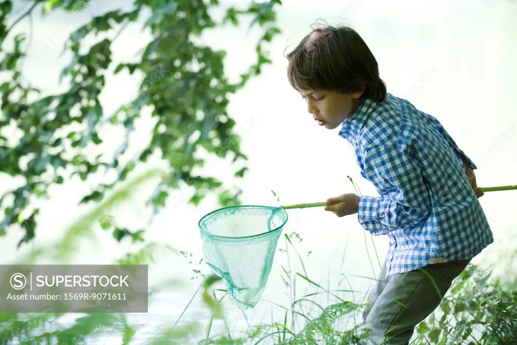 Boy catching tadpoles at water´s edge