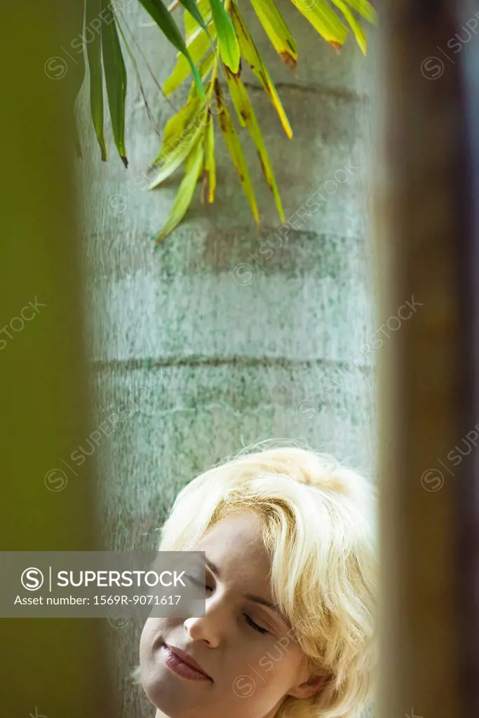 Woman relaxing under palm tree