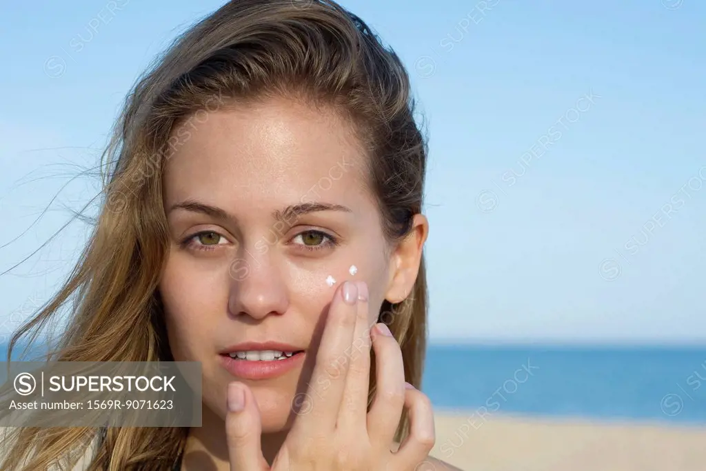 Woman applying sunscreen at the beach, portrait