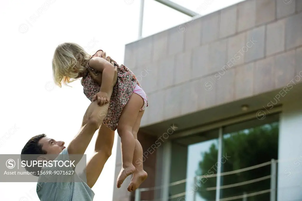 Father lifting young daughter in the air