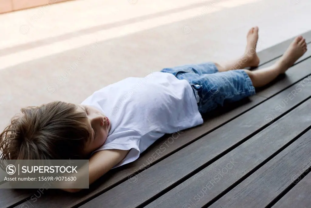 Little boy lying on back on deck