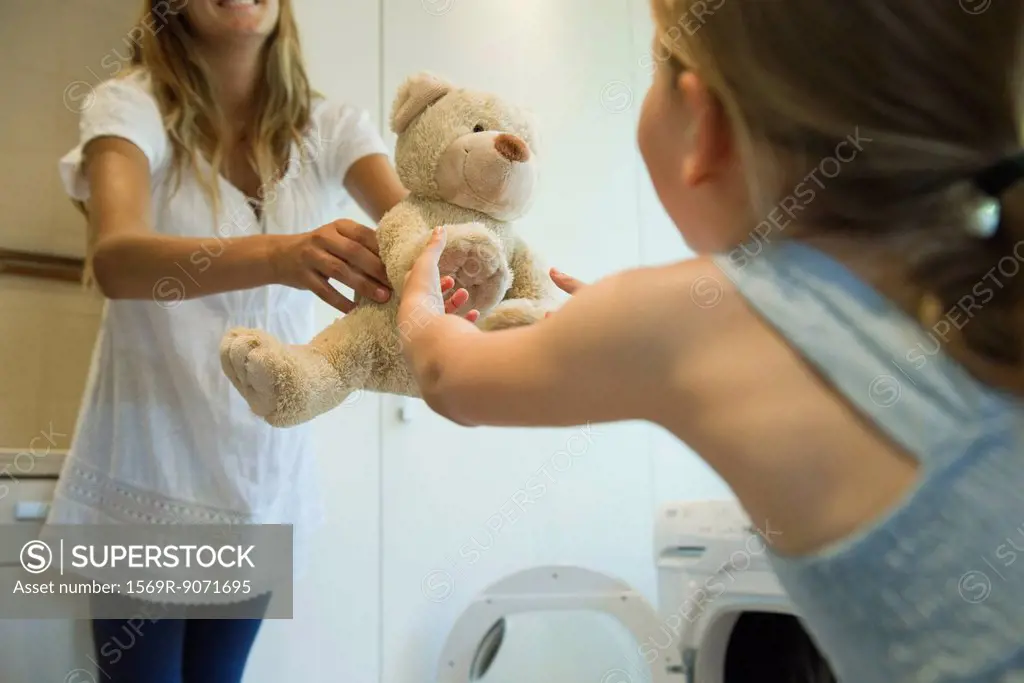 Little girl receiving freshly cleaned teddy bear from mother