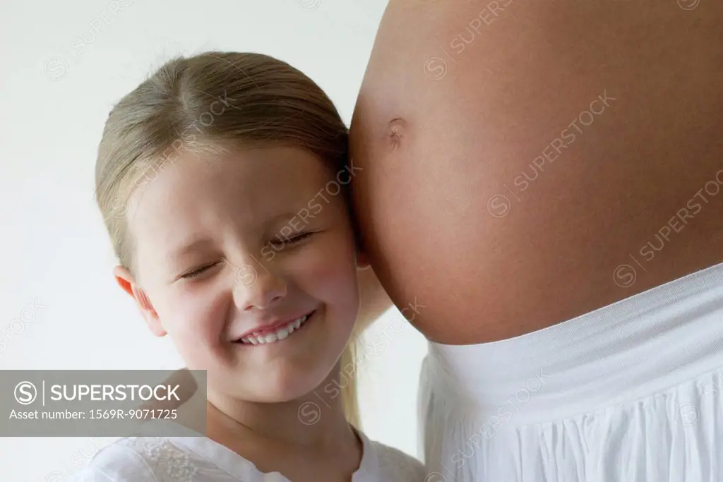 Girl listening to mother´s pregnant belly
