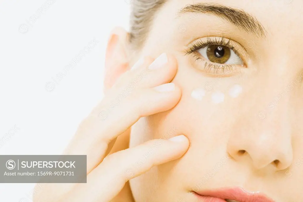 Woman applying undereye cream, close_up, cropped
