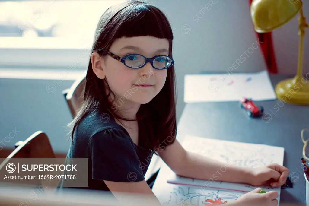 Girl sitting at desk with coloring book