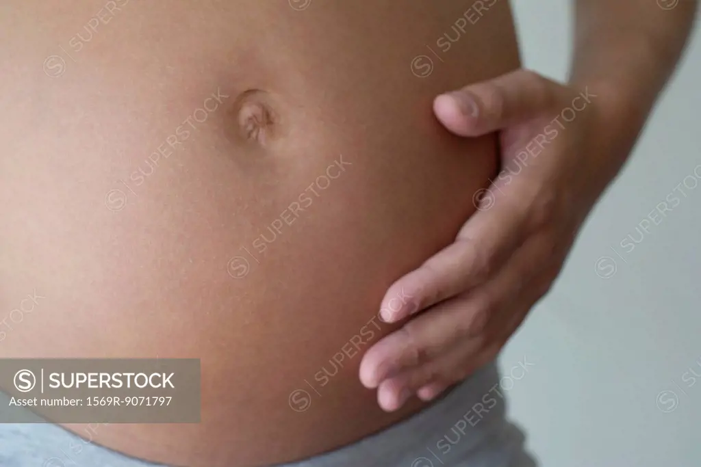 Pregnant woman touching her belly, cropped