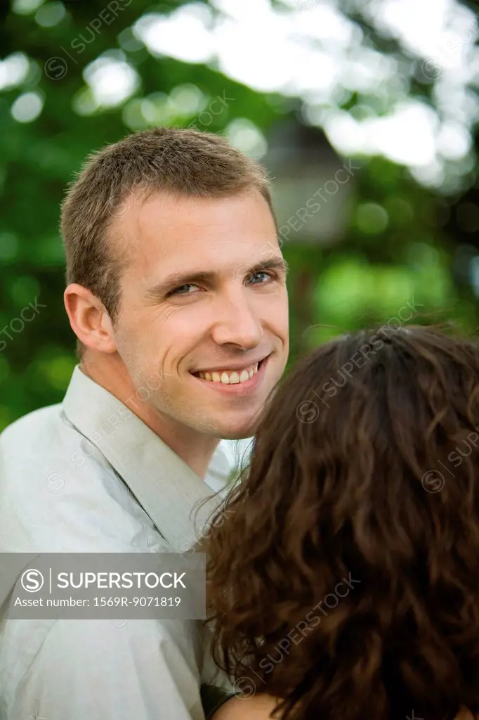 Couple together outdoors, man smiling over shoulder at camera