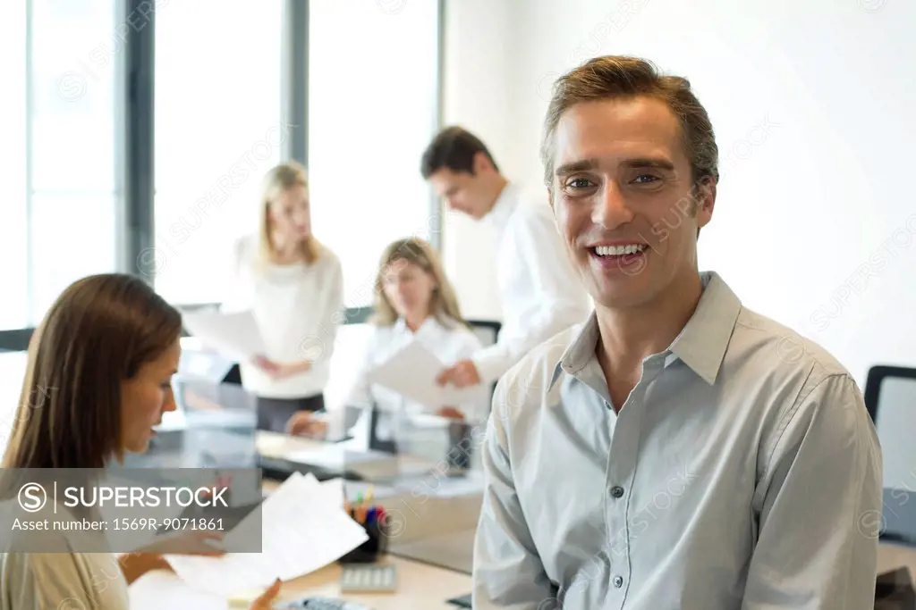 Businessman in office with colleagues, portrait