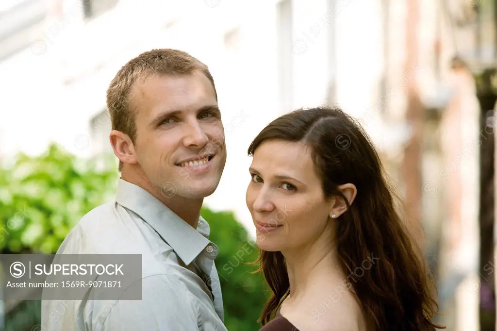 Couple smiling over shoulders at camera, portrait