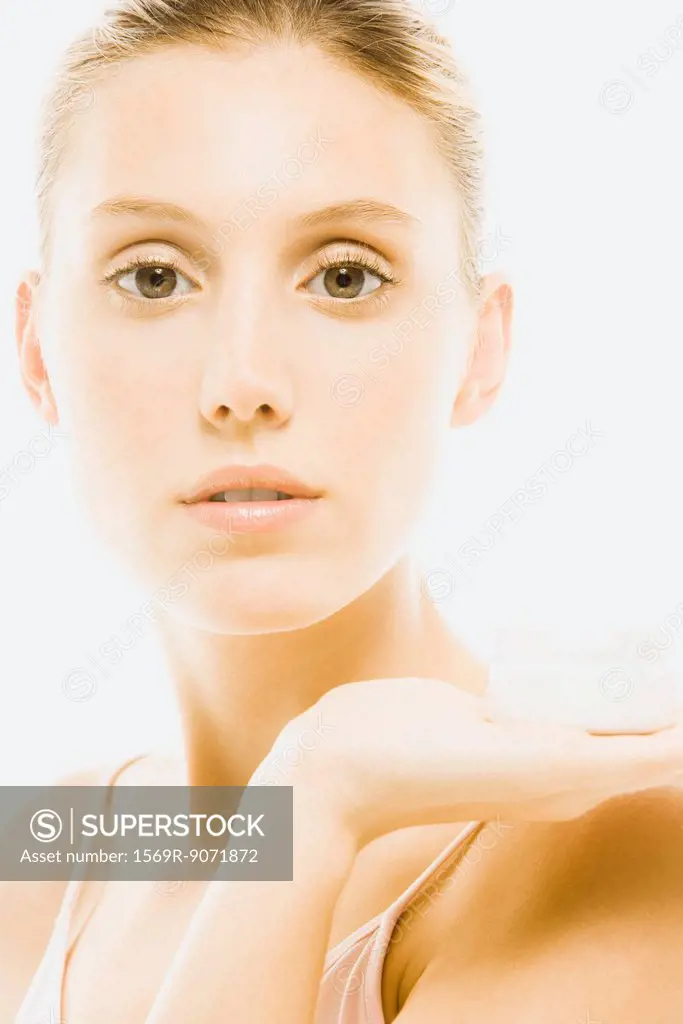 Young woman holding jar of moisturizer, portrait