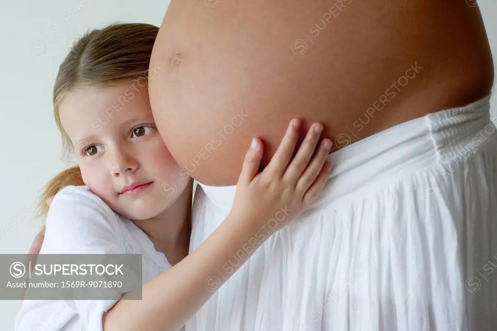 Girl embracing mother´s pregnant belly