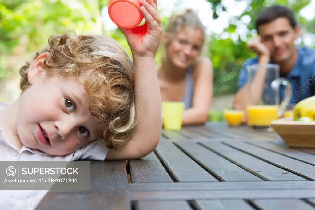 Little boy relaxing at picnic table with parents