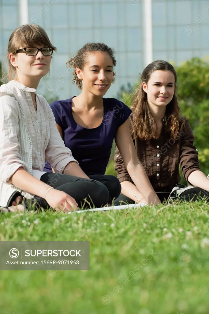 Young women sitting on grass, low angle view