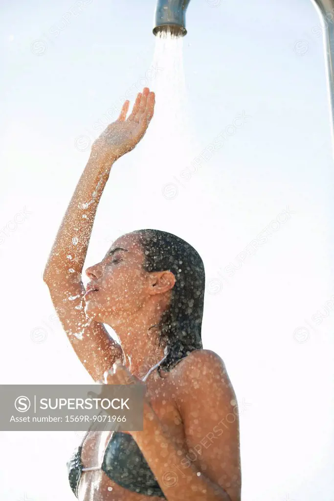 Mid_adult woman enjoying shower outdoors