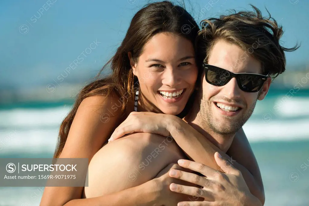 Happy young couple embracing at beach, portrait
