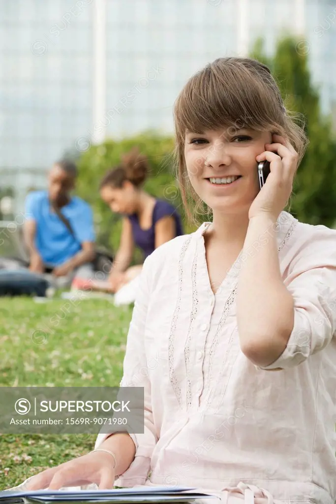 Young woman talking on cell phone outdoors, portrait