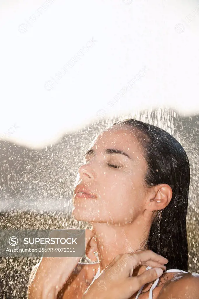 Mid_adult woman enjoying shower outdoors with eyes closed