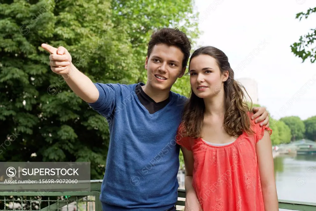 Young couple outdoors, young man pointing into distance, portrait